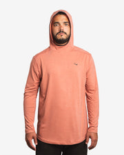 Front view of male model wearing the Jigalode Mighty Jig Performance Fishing Hoodie in rust orange with an all-over tropical plant pattern. The hoodie, with the hood on, offers UPF 30 sun protection and features moisture-wicking properties. The model displays the hoodie's functionality and fashionable appeal.