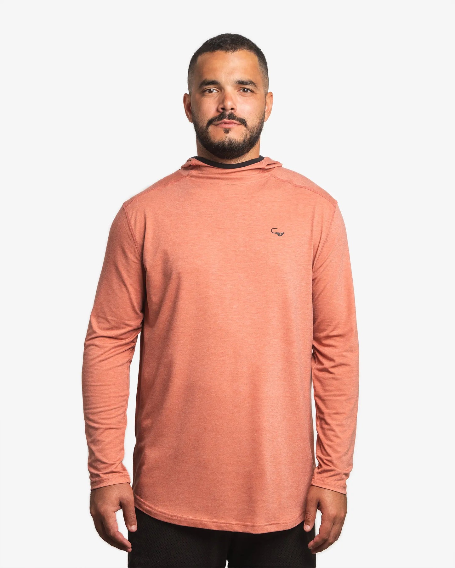 Front view of male model wearing the Jigalode Mighty Jig Performance Fishing Hoodie in rust orange with an all-over tropical plant pattern. The hoodie features a super soft fabric and provides UPF 30 sun protection. The model has the hood down, showcasing the stylish design.
