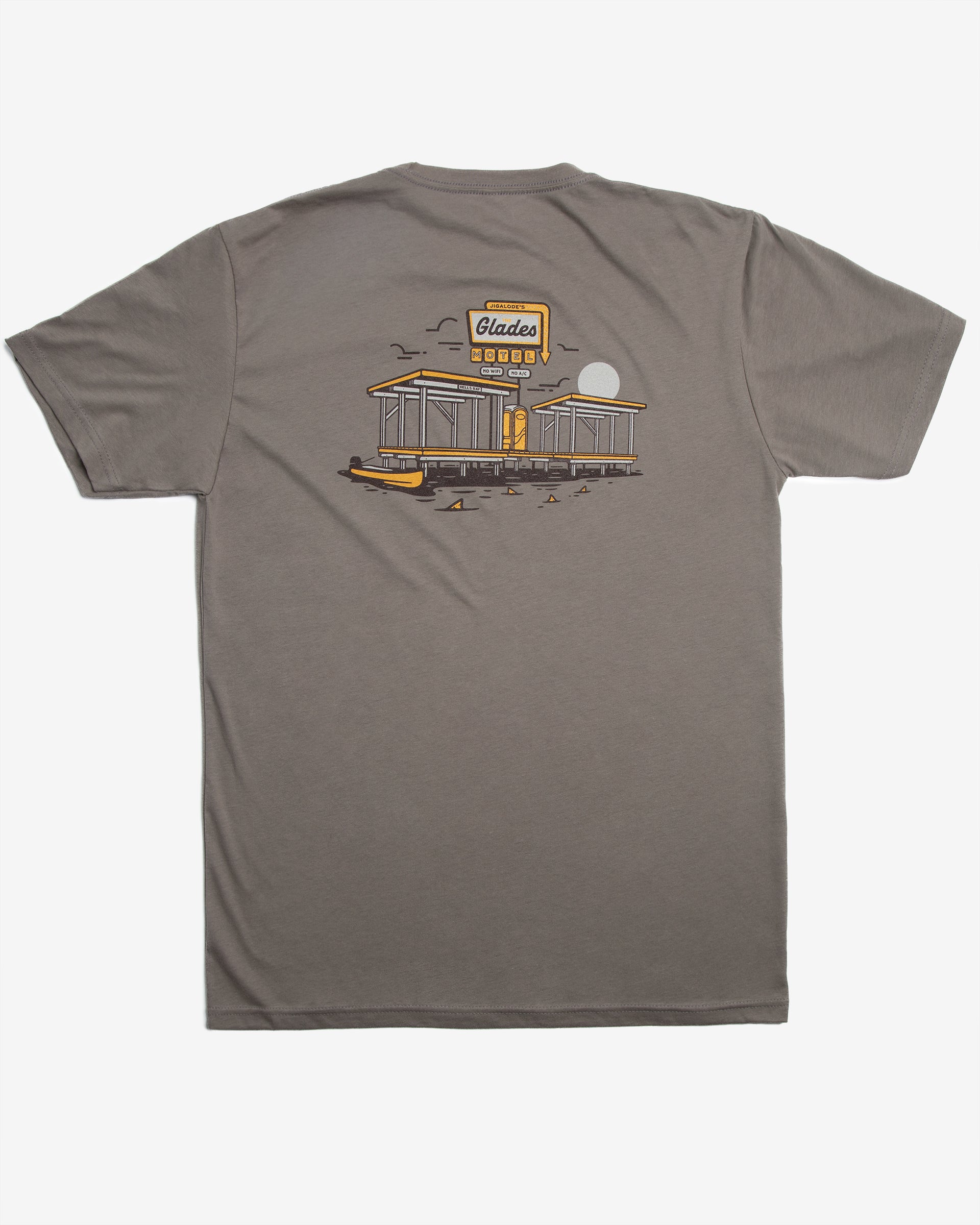 Front flat view of the Jigalode 'Glades Motel' t-shirt in warm gray. The short sleeve cotton fishing t-shirt showcases artwork of an everglades chickee with a vintage motel sign above it that reads 'The Glades Motel: No Wi-Fi, No A/C.' The design also features a gheenoe in the water with redfish tails surrounding it.