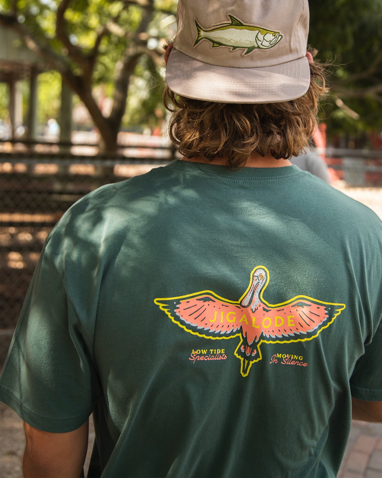 Model wearing the green Jigalode roseate spoonbill fishing t-shirt and tarpon hat