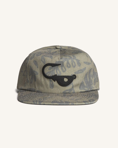 Front view of the Jigalode "Mighty Jig" 5-Panel hat. The hat is a moss green color with a tropical plant pattern printed all over. The front of the fishing hat features the Jigalode "Mighty Jig" logo.