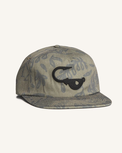 Angled view of the Jigalode "Mighty Jig" 5-Panel hat. The hat is a moss green color with a tropical plant pattern printed all over. The front of the fishing hat features the Jigalode "Mighty Jig" logo.