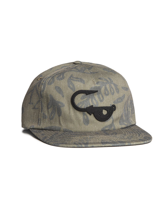 Angled front view of the Jigalode "Mighty Jig" 5-Panel hat. The hat is a moss green color with a tropical plant pattern printed all over. The front of the fishing hat features the Jigalode "Mighty Jig" logo.