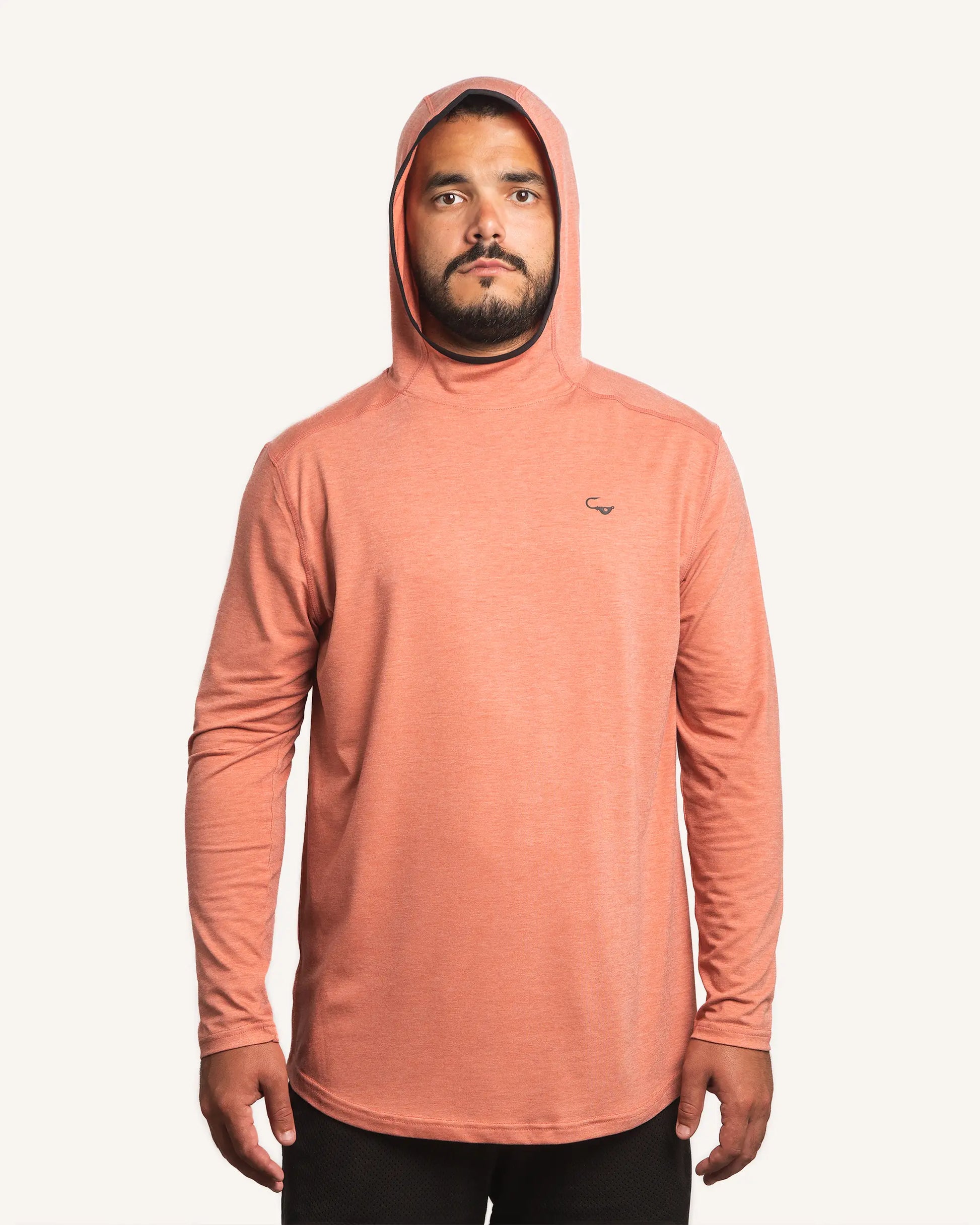 Front view of male model wearing the Jigalode Mighty Jig Performance Fishing Hoodie in rust orange with an all-over tropical plant pattern. The hoodie, with the hood on, provides UPF 30 sun protection and showcases its sleek design. The model demonstrates the hoodie's fit and style.