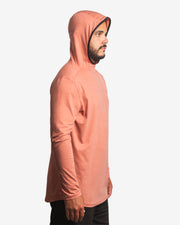 Side view of male model wearing the Jigalode Mighty Jig Performance Fishing Hoodie in rust orange with an all-over tropical plant pattern. The hoodie, with the hood on, provides UPF 30 sun protection and showcases its sleek design. The model demonstrates the hoodie's fit and style.
