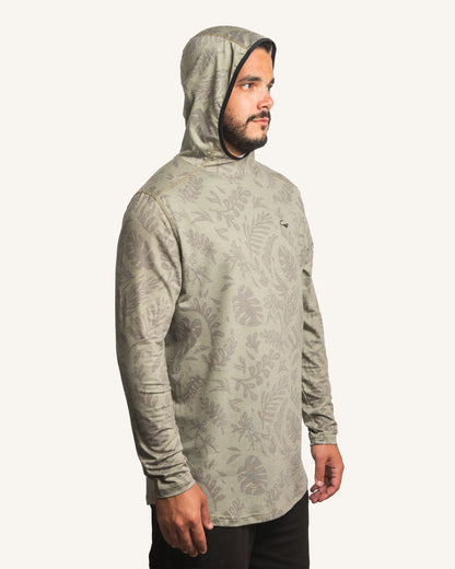 Side view of male model wearing the Jigalode Mighty Jig Performance Fishing Hoodie in moss green with an all-over tropical plant pattern. The hoodie, with the hood on, offers UPF 30 sun protection and features moisture-wicking properties. The model displays the hoodie's functionality and fashionable appeal.
