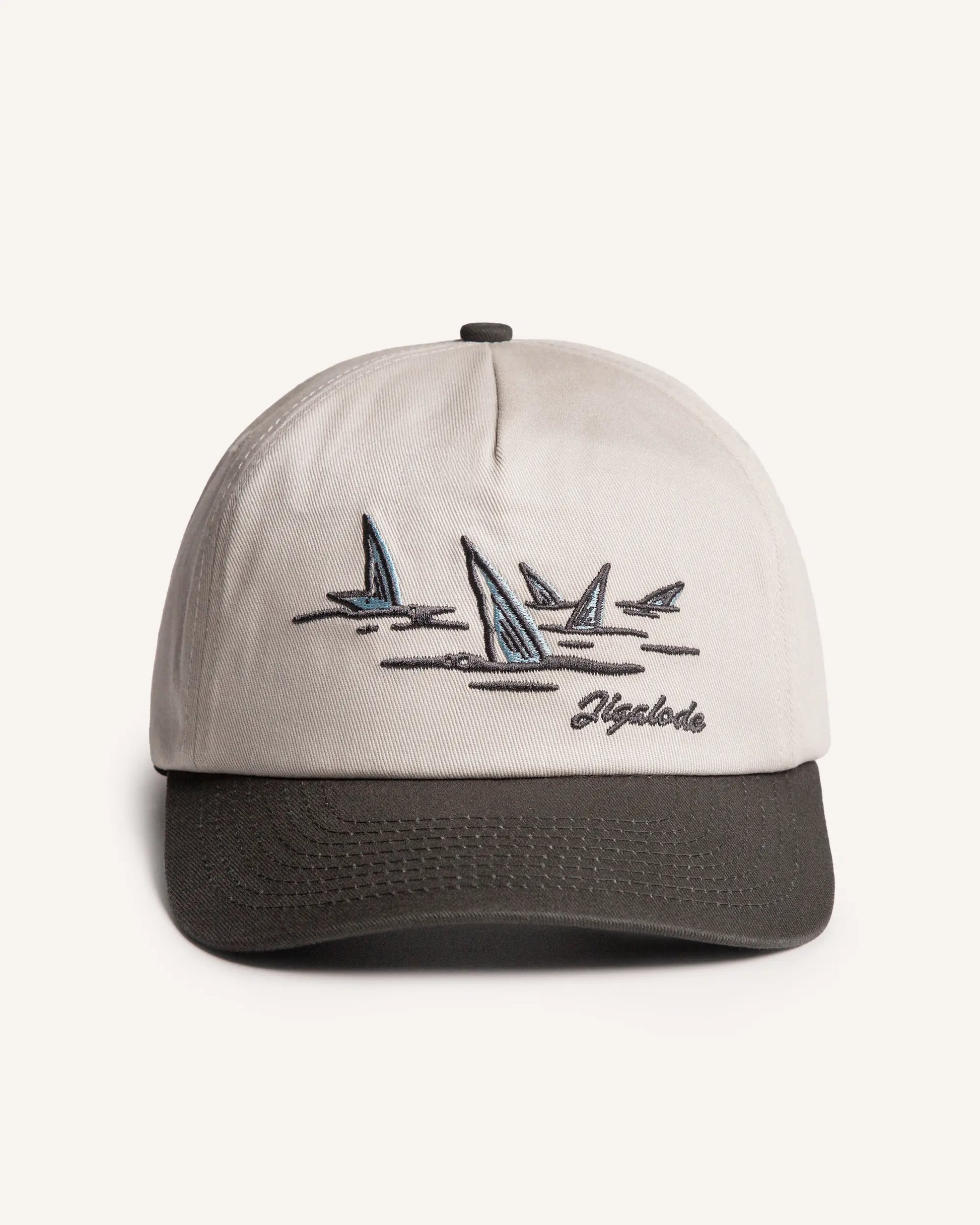 Front shot of the Tailer Snapback. It is a tone toned hat (Natural crown with a dark gray brim) retro styled snapback with a school of bonefish tails embroidered in the front.