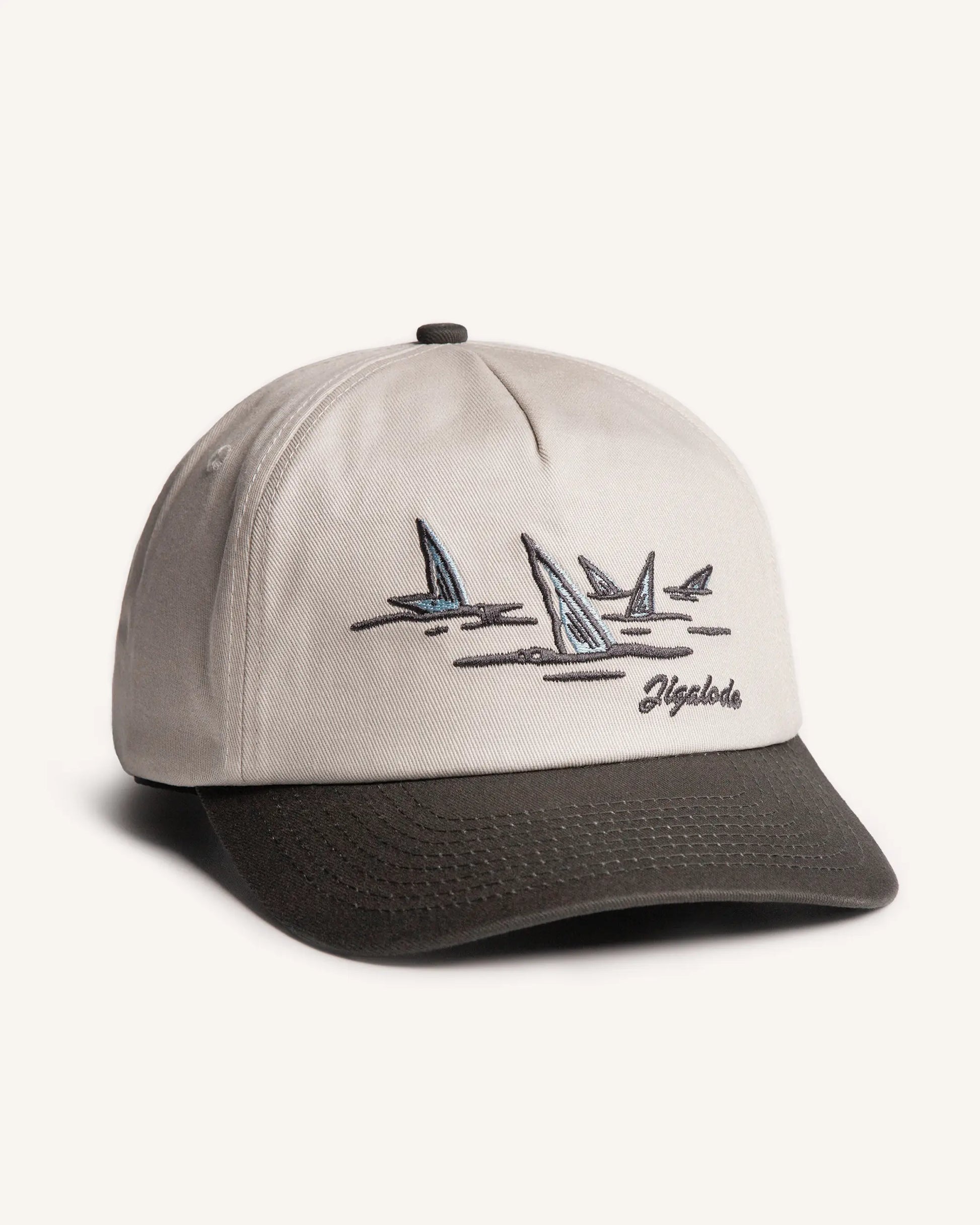Side shot of the Tailer Snapback. It is a tone toned hat (Natural crown with a dark gray brim) retro styled snapback with a school of bonefish tails embroidered in the front.
