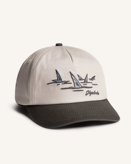 Side shot of the Tailer Snapback. It is a tone toned hat (Natural crown with a dark gray brim) retro styled snapback with a school of bonefish tails embroidered in the front.