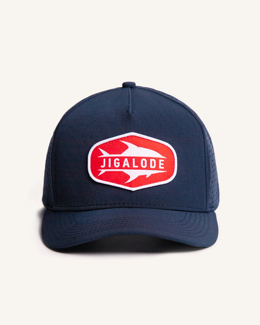Front shot of the Permit Performance Snapback. Navy blue hat with laser perforated holes and a red and white woven patch of a permit fish.