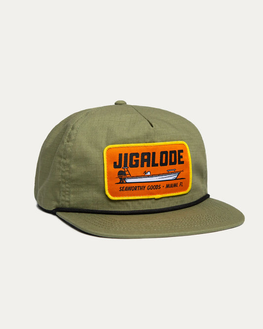 Side of the Seaworthy fishing Snapback. It is green with an orange patch with a yellow border. The patch features a poling skiff that says "Seaworthy Goods"